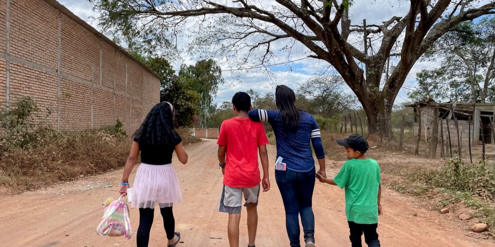 Children at Montaña de Luz HIV children's home in Honduras walk along a dirt path to the nearby town